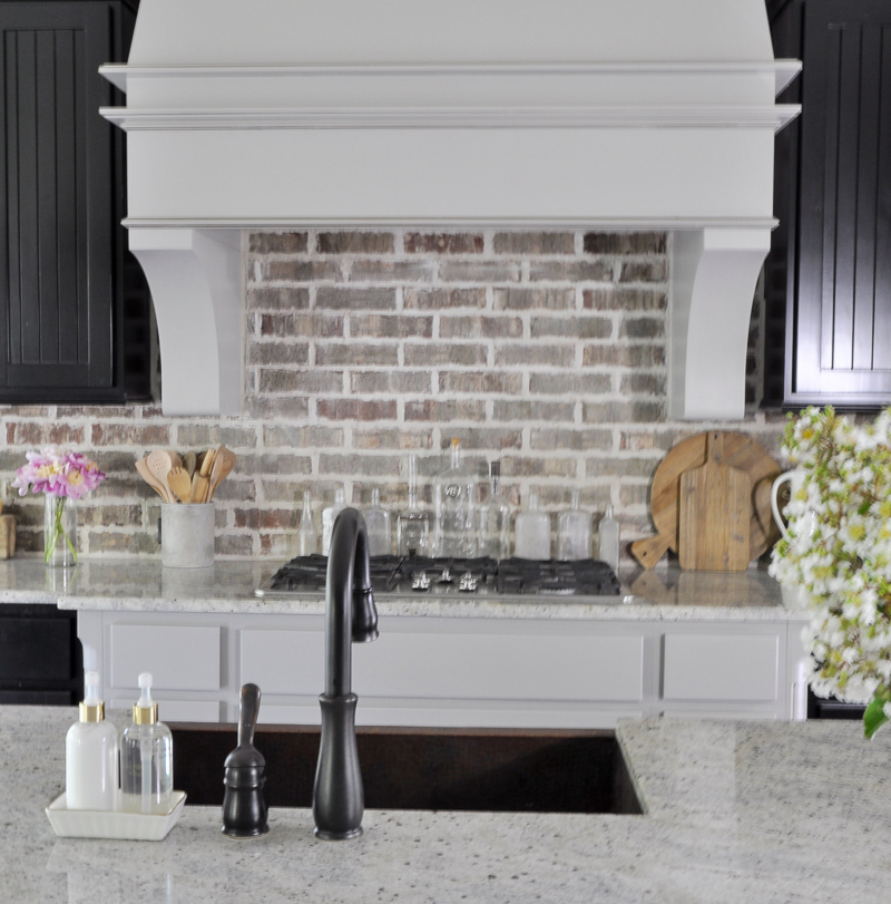 Statement vent hood and brick backsplash in beautiful kitchen