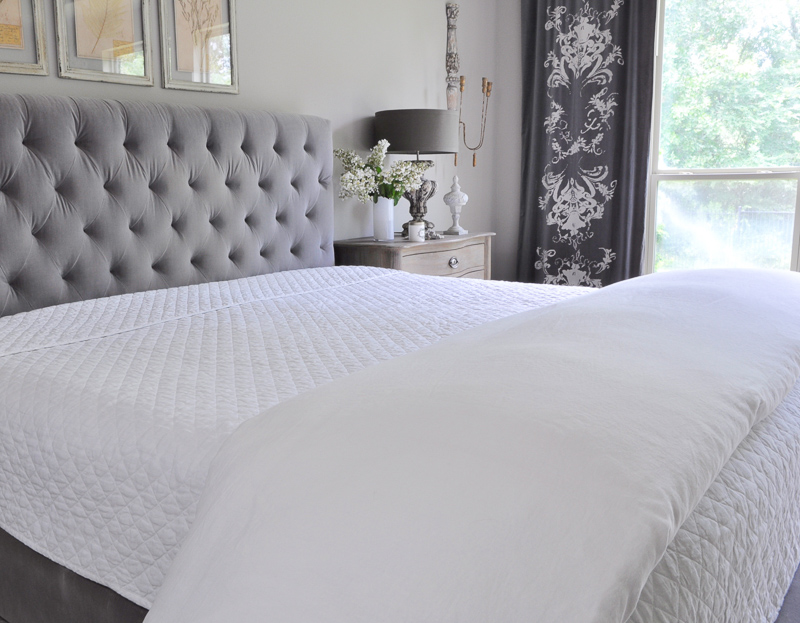 white linen bedding basics on beautiful gray tufted bed