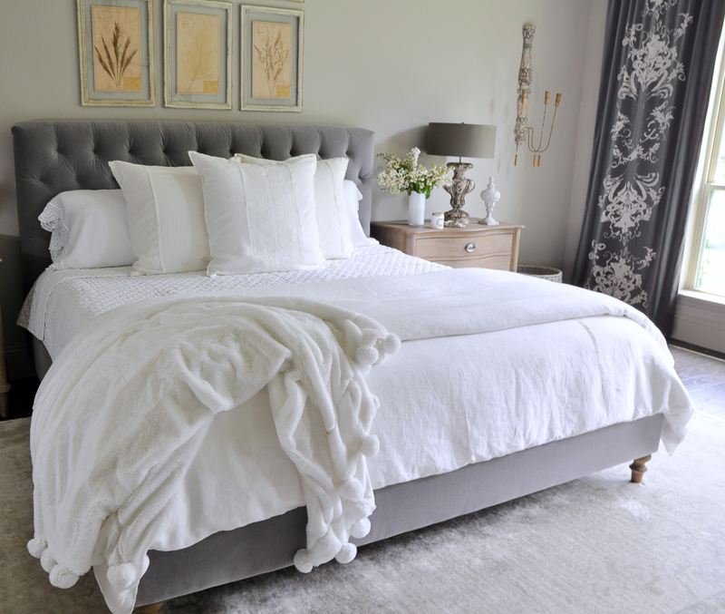 all white bedding with linen pillows and gorgeous pom pom thr