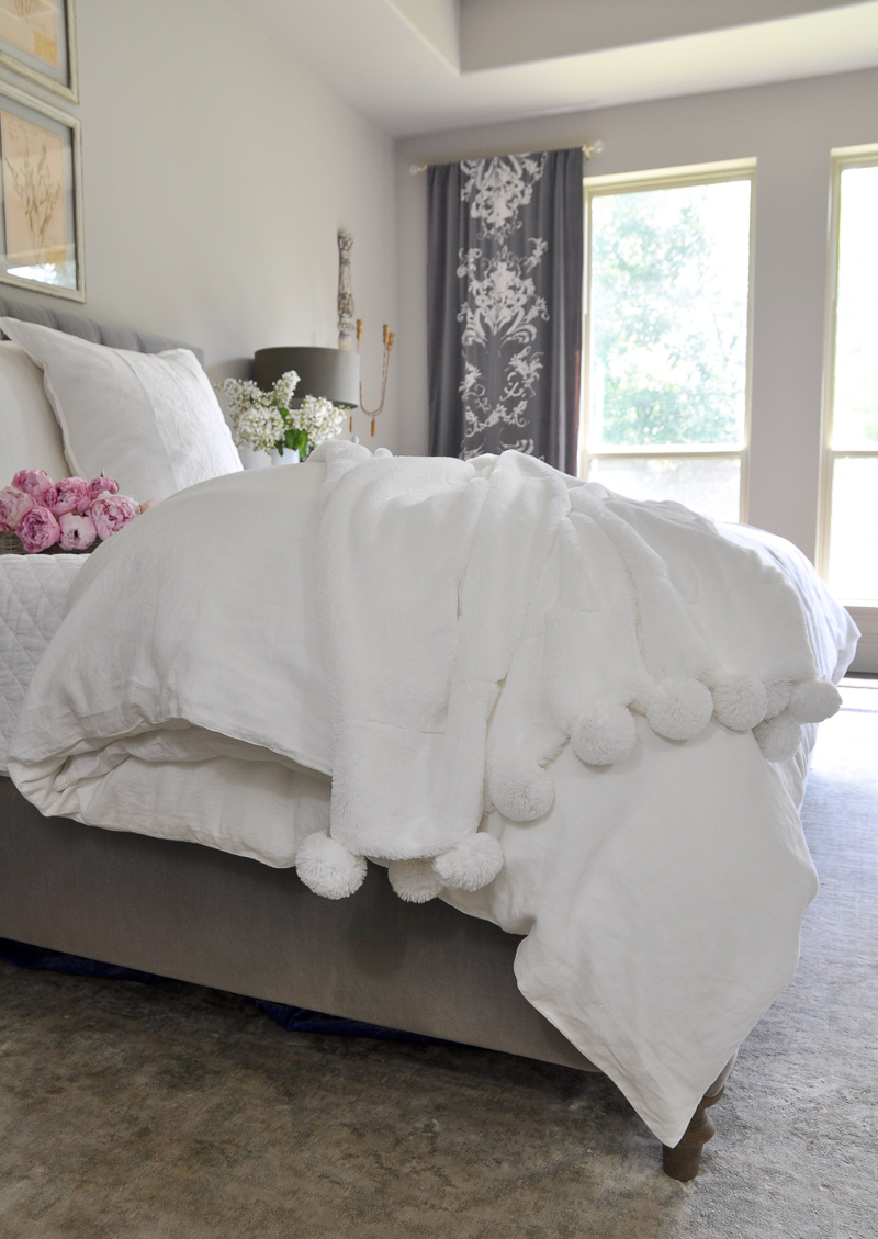 dreamy white pom pom throw in beautiful bedroom with vintage