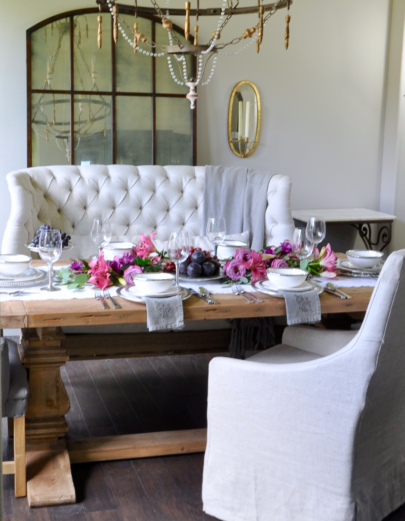 beautiful dining room set for a dinner party with pink and puple flowers