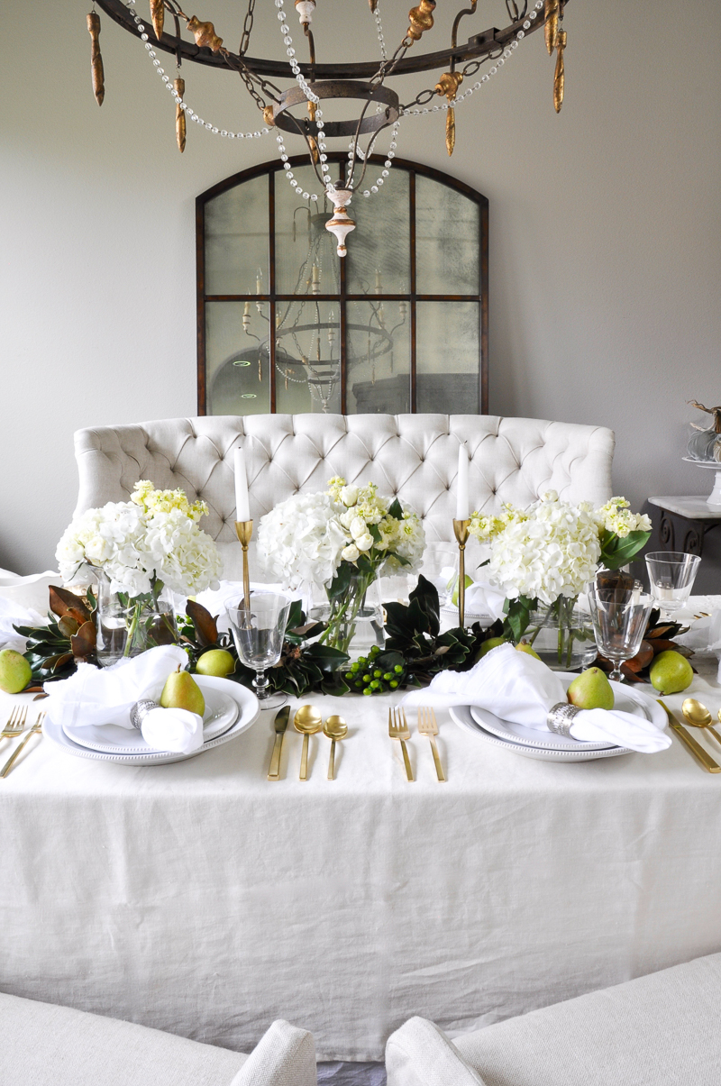 beautiful-holiday-table-with-gold-silverware-white-and-greenery