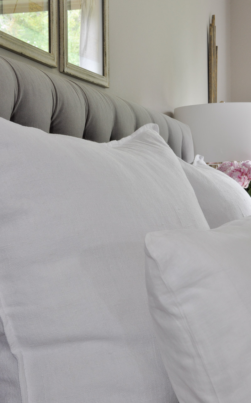 crisp white linen bedding on gray tufted bed