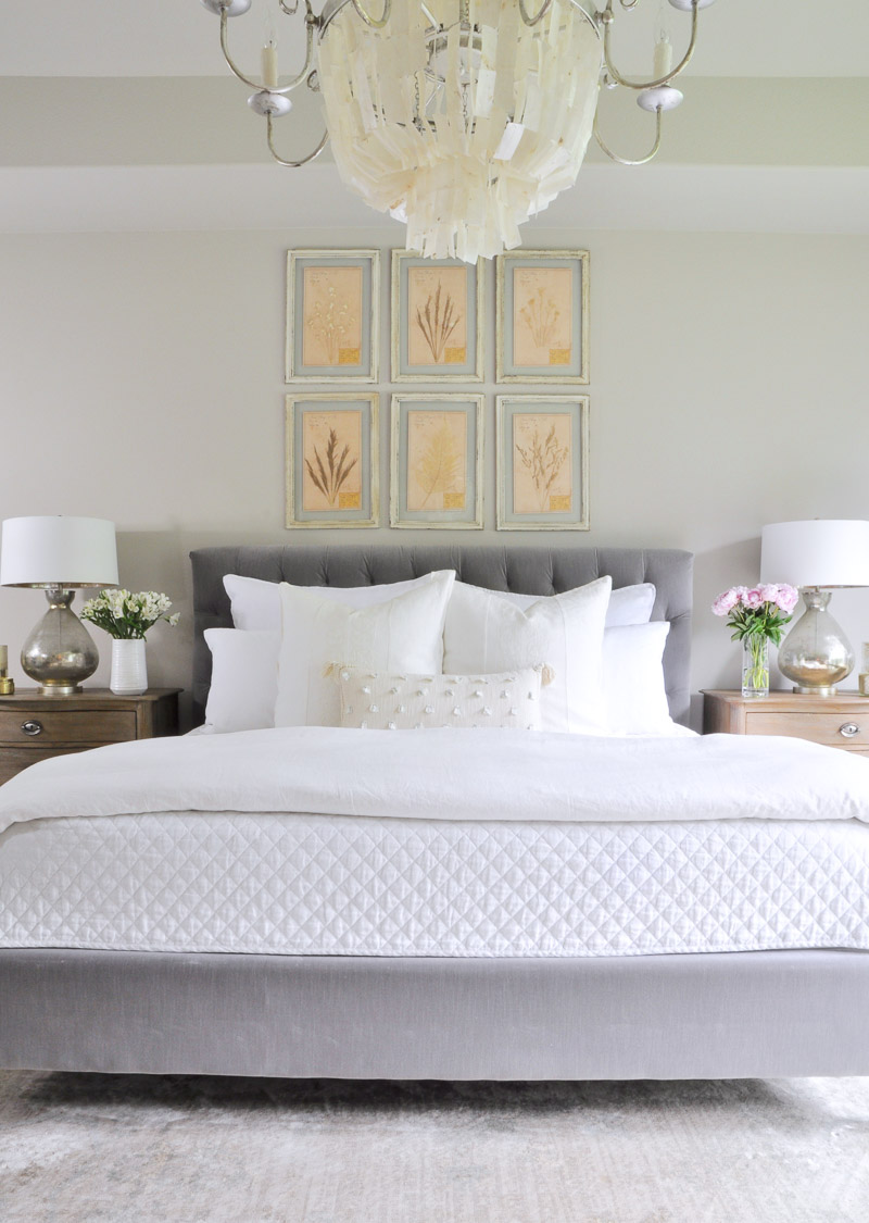 Bedroom with gray tufted bed and white bedding 