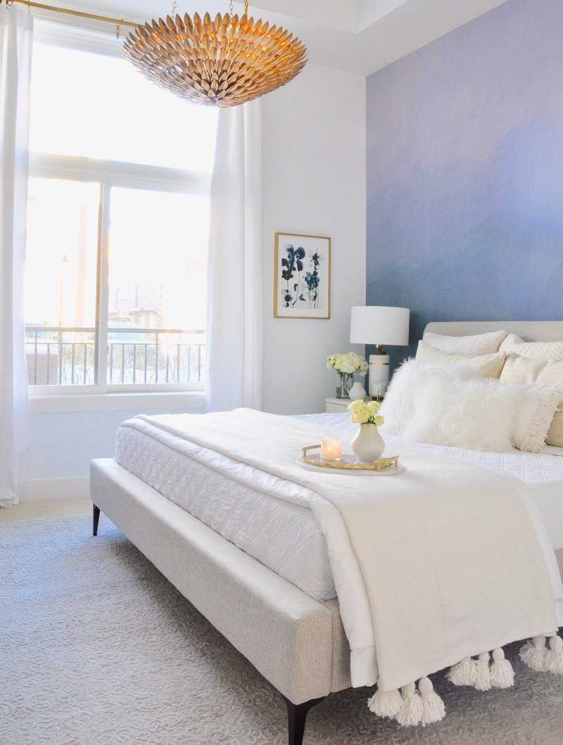 bedroom with layered white bedding and blue accent wall