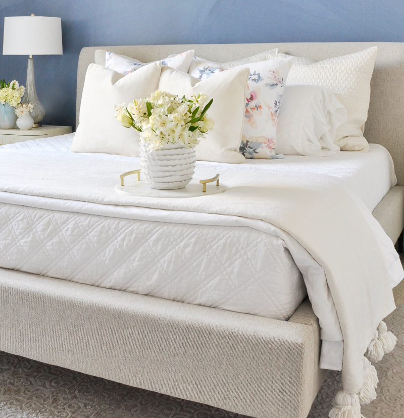 beautiful blue and white spring bedroom with white and floral bedding