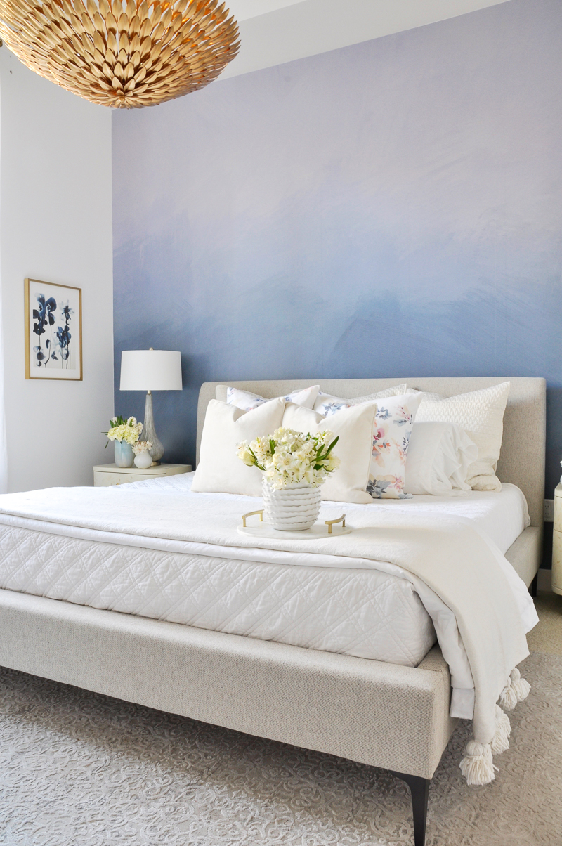 beautiful blue and white spring bedroom with white and floral bedding