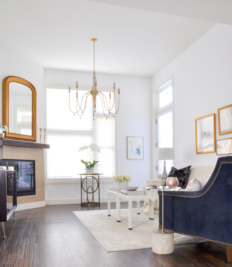 bright white living room with gold accents and blue velvet chair