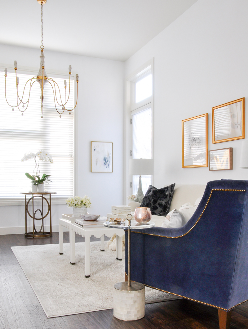 white living room with gold accents and blue velvet chair