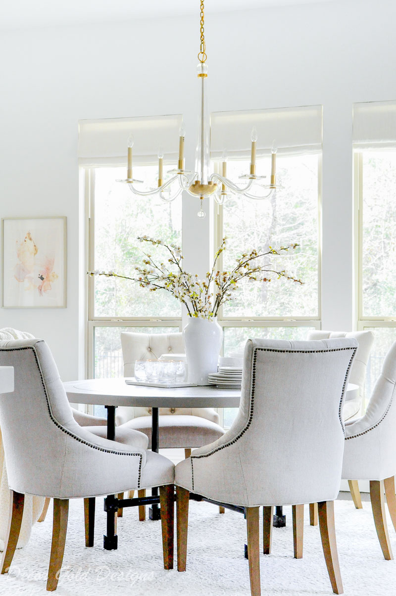 Breakfast room round table six chairs vase branches